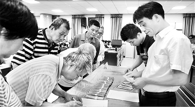 圖為張小華（右一）生前在三角塘鎮(zhèn)給部分困難群眾清退水廠(chǎng)違規(guī)收取的費(fèi)用。（資料圖片）